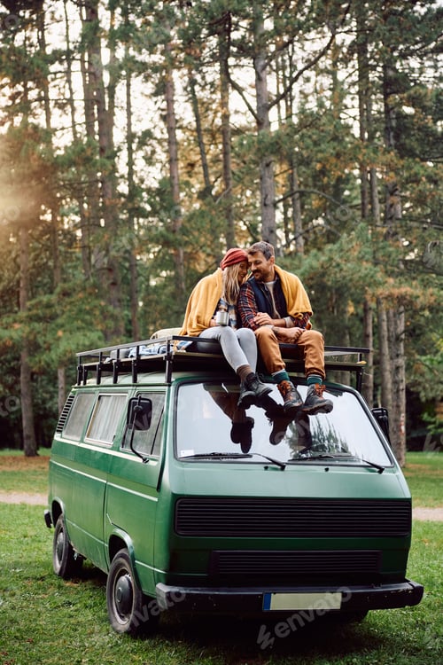 Preview: Happy couple of campers enjoying in autumn day while being wrapped in blanket in nature.