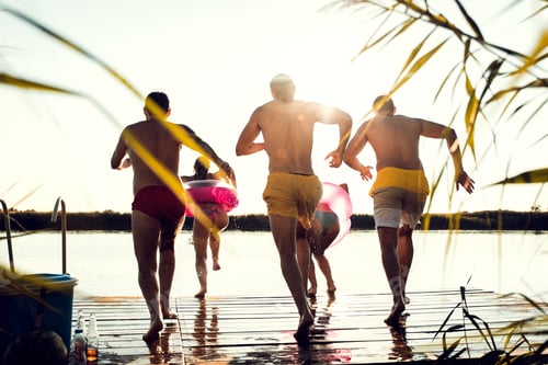 Preview: Rear view of friends having fun enjoying a summer day swimming and jumping at the lake.