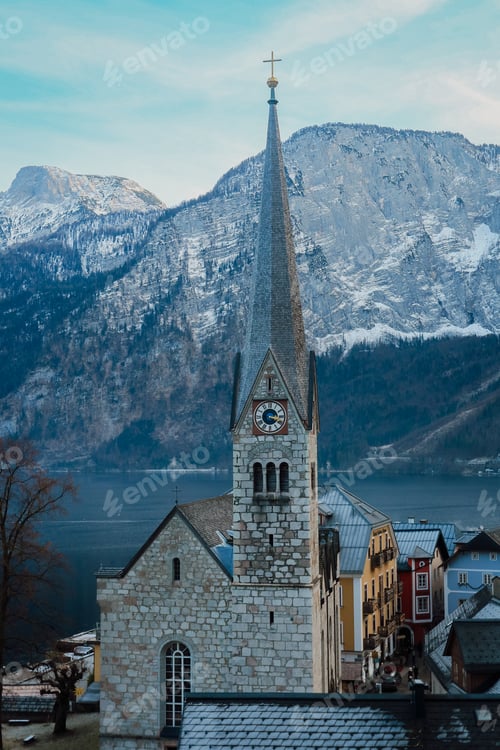 Preview: Snow-capped mountains tower over the historic church in Hallstatt, Austria