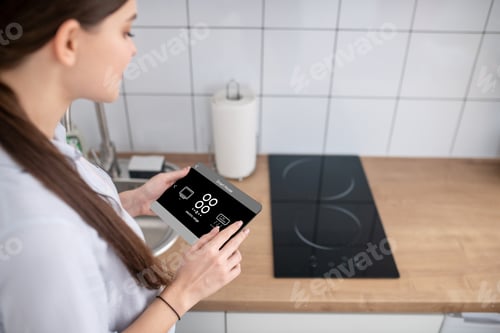 Preview: Housewife turning on the cooktop using a gadget