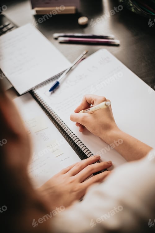Preview: Top view of the back of a young woman studying and working on his home desk,