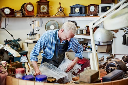 Preview: A clock maker busy in his workshop wrapping an antique clock. .