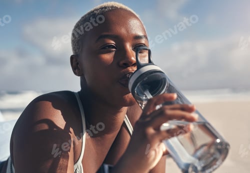Preview: Shot of a sporty young woman drinking water while out for a workout