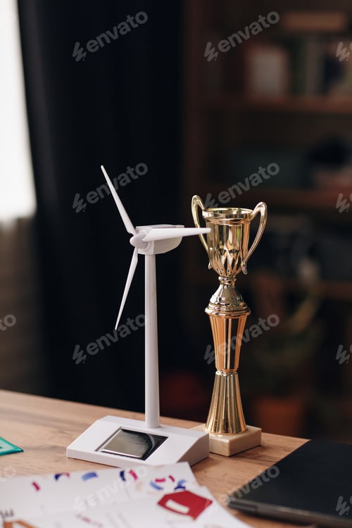 Preview: Closeup of Wind Turbine Model and Trophy Standing on Desk in Teenager Room