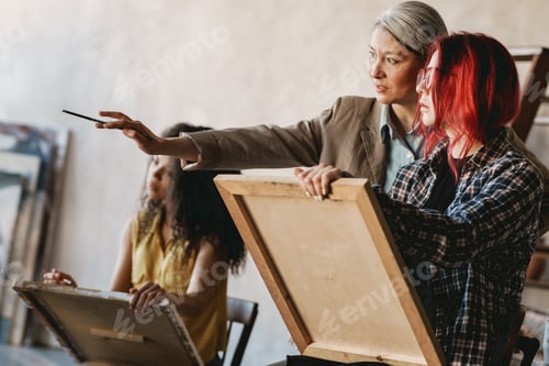 Preview: Mature teacher talking with her student during class in art school