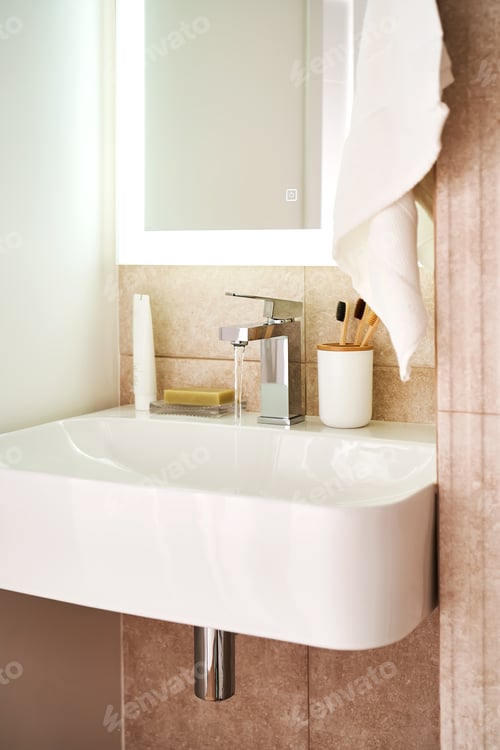Preview: Bathroom sink with toothbrushes and running water.