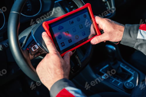 Preview: Car mechanic holds tablet for checking the electronic systems of cars