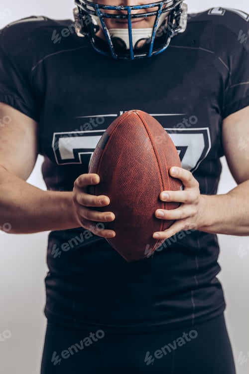 Preview: Determined Player Holding Football Wearing Helmet and Pads