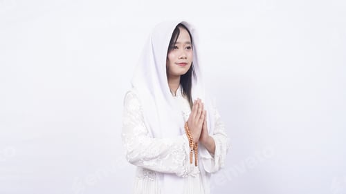 Preview: Asian muslim woman wearing prayer beads welcoming guests / Ied Fitr Greeting in white background