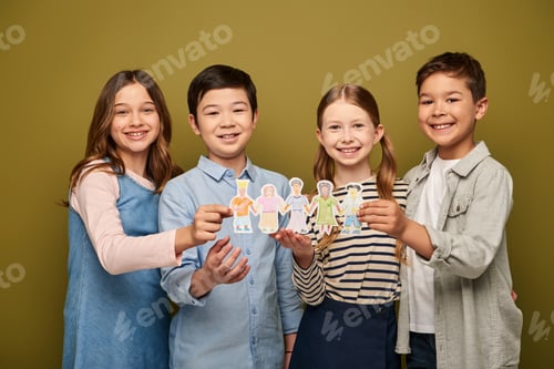 Preview: Preteen kids in casual clothes holding drawn paper characters and smiling at camera during