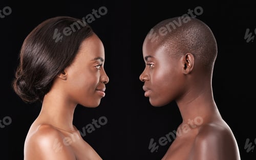 Preview: Perfect profiles. Two beautiful african women standing face to face against a black background.