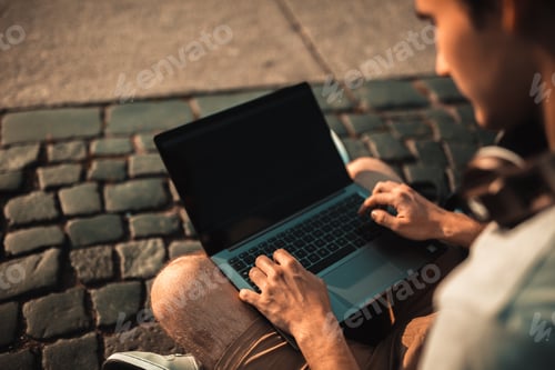 Preview: Young millennial student using technology outdoor. Stylish Man coding on laptop new app