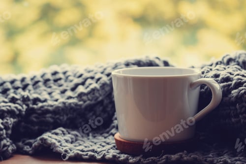 Preview: Cozy home at autumn day. Woolen scarf and cup of tea on the windowsill