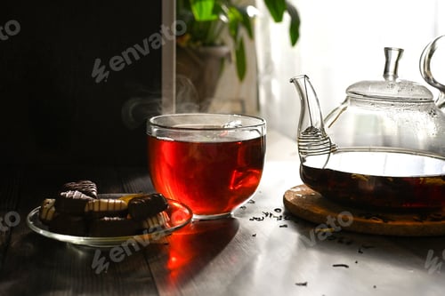 Preview: freshly brewed tea in a transparent teapot with a transparent mug, steam in a mug, tea party with sw
