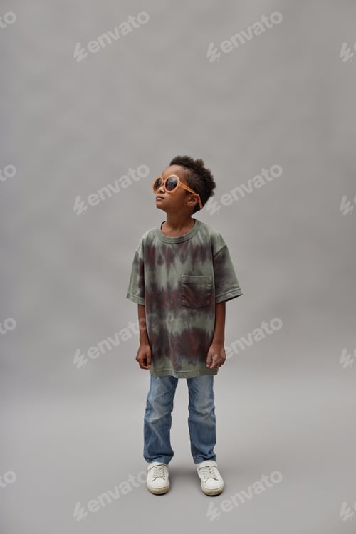Preview: Preteen Black Boy Wearing Sunglasses Standing on Gray Background in Studio