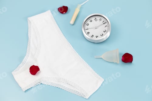 Preview: White panties, menstrual cup, tampon, rose petals and an alarm clock.