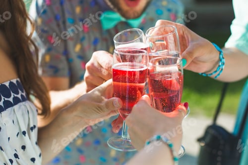 Preview: Friends at the party bump glasses, rejoice and have a good time. Pink champagne in glasses.