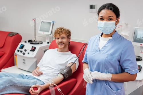 Preview: multiracial healthcare worker in medical mask and latex gloves looking at camera near blurred man
