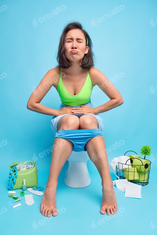 Preview: Stomach issues concept. Unhappy brunette Asian woman suffers from strong pain period cramps or diarr