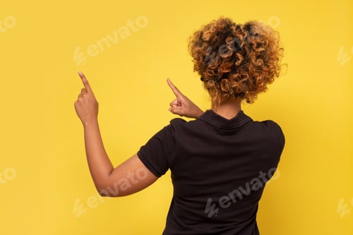 Preview: Rear view of a african woman with her hand up pointing. Pay attention to this information.