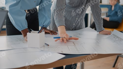 Preview: Close up of architects analyzing blueprints plans on table