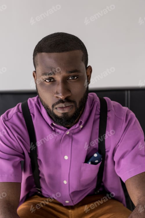 Preview: portrait of thoughtful african american stylish man on black sofa isolated on grey