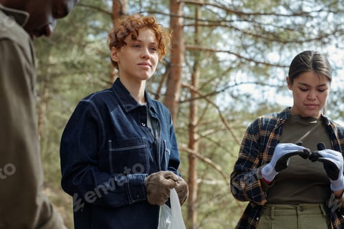 Preview: Young Caucasian Woman Volunteering Outdoors with Diverse Group Collecting Trash