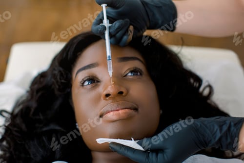 Preview: Close up view of hands of female doctor cosmetologist making rejuvenating therapy, facial injections