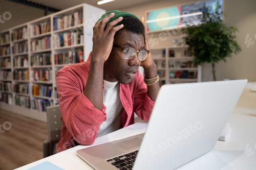 Preview: Unhappy black guy freelancer or student look at laptop screen shocked by error operational problems.
