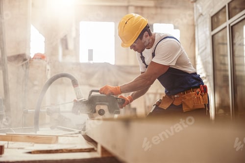Preview: Male builder using wood cutting circular saw machine in workshop