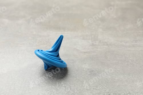 Preview: Blue spinning top on grey textured background, closeup. Space for text