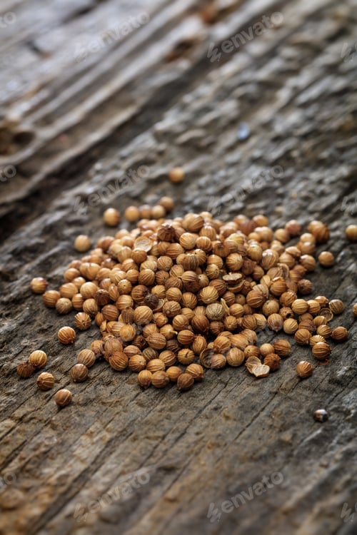 Preview: Dried coriander seeds in a pile set on old wooden surface