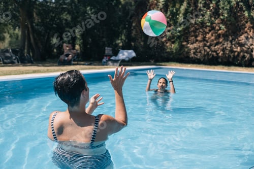 Preview: Mother and daughter play fun with an inflatable ball in a pool
