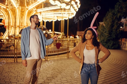 Preview: Funny love couple joking in night amusement park