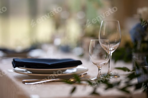 Preview: Closeup of a festive table with white dishes and glasses, blurred background
