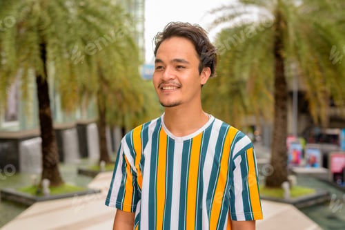 Preview: Portrait of handsome multi-ethnic young man wearing colorful shirt outdoors during summer while