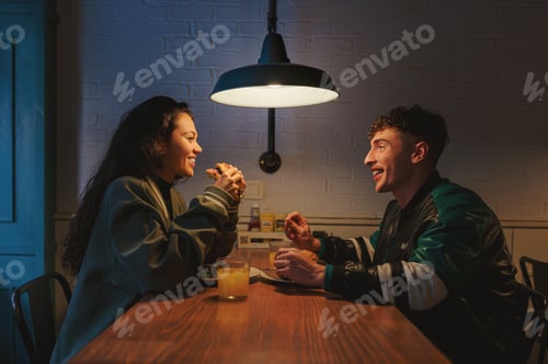 Preview: Happy couple enjoying burgers and drinks on a date night at restaurant