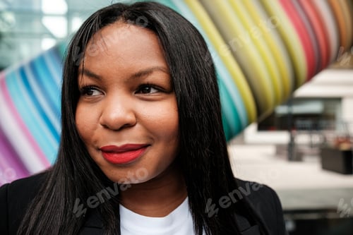 Preview: Young black businesswoman smiling near colorful modern architecture