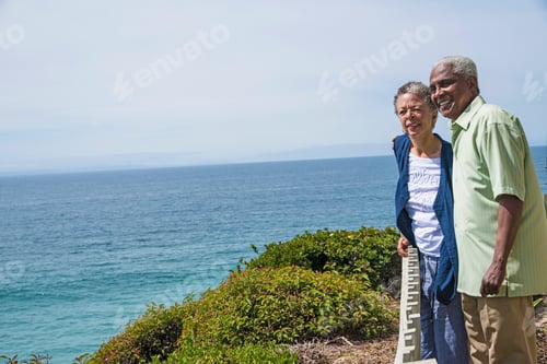 Preview: Senior couple standing outside, near ocean, looking at view