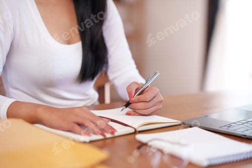 Preview: Businesswoman sitting taking notes intensively and doing assigned tasks happily and purposefully.
