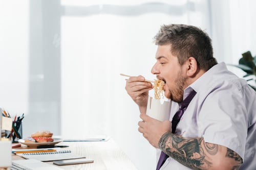 Preview: overweight businessman eating noodles at workplace in office