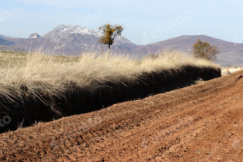 Preview: muddy dirt road, snowy mountains and dry grass