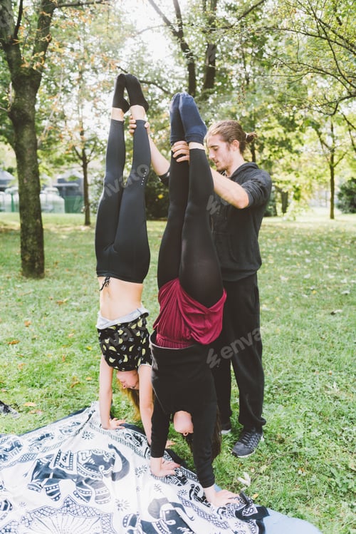 Preview: Man teaching two young girls how to handstand outdoor