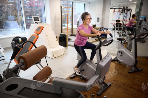 Preview: Adult woman wearing sportswear doing sport exercise on cycle track in gym