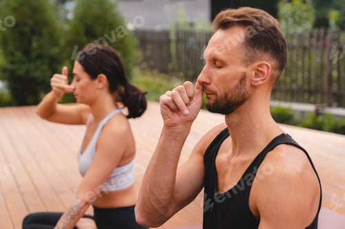 Preview: Close up photo of two caucasian yogi breathing deeply with one nostril during yoga class