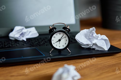 Preview: Workplace, wooden office desk with clock, sheet of paper, laptop, notebook, crumpled paper