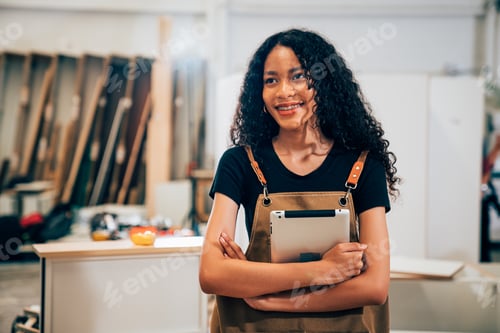 Preview: Young woman working as carpenter in a small carpentry workshop.