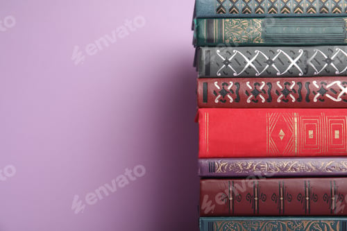 Preview: Stack of hardcover books on violet background. Space for text