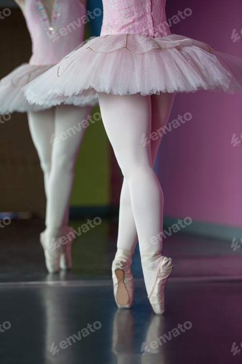 Preview: Graceful ballerina standing en pointe in front of mirror in the ballet studio