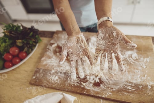 Preview: Women's hands in flour against the background of a kitchen board and a plate of vegetables